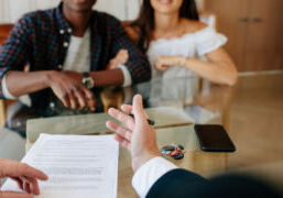 Home buyers at table with agent. House keys and contract on the table.